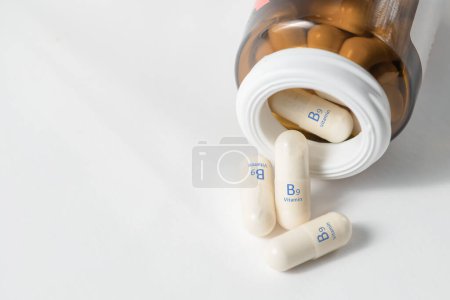Foto de Vitamin B9. Capsules with folic acid, necessary for the growth and development of the circulatory and immune systems. White capsules of vitamin B9 or folic acid are scattered with copy space - Imagen libre de derechos