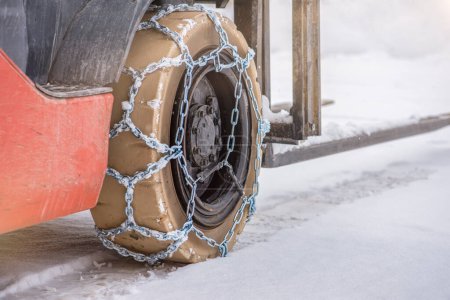 Photo for Cargo loader in winter on snow. The loader ride on snow with chains on the wheels to reduce slippage and spin. Driving safety in winter conditions. - Royalty Free Image