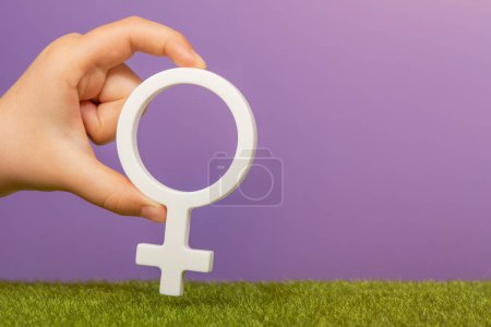 Foto de Símbolo de género de una mujer. Símbolo de mujer en manos sobre fondo púrpura con espacio de copia. El concepto de mujer líder o igualdad de género. Foto de alta calidad - Imagen libre de derechos