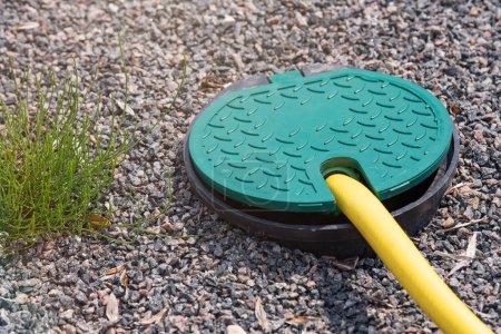 Photo for A plastic hatch in the garden covering the connection point for the irrigation hose. A protective hatch in the garden for connecting water and watering plants. High quality photo - Royalty Free Image