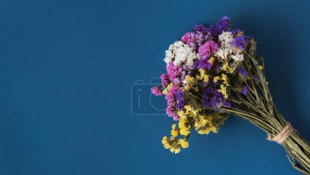 Téléchargez les photos : Bouquet de fleurs sauvages sèches multicolores sur fond bleu. Pose plate. Espace de copie. Modèle de carte de vœux - en image libre de droit