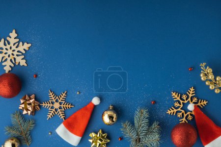 Foto de Juguetes de Navidad en el fondo azul. Fondo navideño festivo con copos de nieve de madera, ramas de árboles y sombreros de Santa Claus. Acostado. Copiar espacio. Feliz Navidad y Feliz Año Nuevo - Imagen libre de derechos