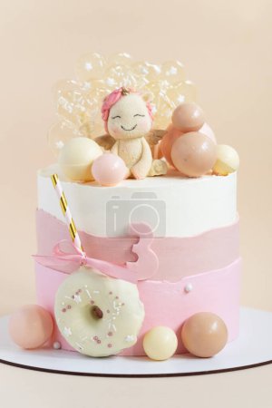 Foto de Pastel de cumpleaños para una niña con glaseado de queso crema pastel rosa decorado con figura de unicornio, esferas de chocolate y caramelos sobre el fondo beige. - Imagen libre de derechos