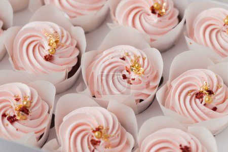 Photo for Set of cupcakes with pink whipped cream top decorated with edible golden petals and red dried berries. Close-up shot of cupcakes in the white background. Macro shot - Royalty Free Image