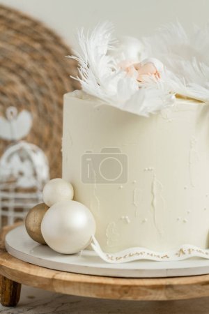 Christening cake with white cream cheese frosting decorated with mastic newborn baby sleeping on the edible angel wings. Little baby angel sleeping. Baby born celebration.