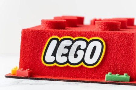 Foto de KYIV, UCRANIA - 11 de octubre: Tarta de Lego de cumpleaños en forma de ladrillo lego rojo rociado con recubrimiento de terciopelo de chocolate sobre el fondo blanco. - Imagen libre de derechos