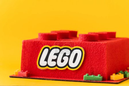Foto de KYIV, UCRANIA - 11 de octubre: Tarta de Lego de cumpleaños en forma de ladrillo lego rojo rociado con recubrimiento de terciopelo de chocolate sobre el fondo amarillo. - Imagen libre de derechos