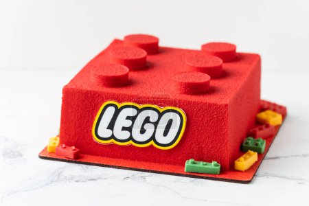 Foto de KYIV, UCRANIA - 11 de octubre: Tarta de Lego de cumpleaños en forma de ladrillo lego rojo rociado con recubrimiento de terciopelo de chocolate sobre el fondo blanco. - Imagen libre de derechos