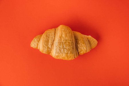 Foto de Colocación plana de croissant recién horneado sobre el fondo rojo. Pastelería tradicional francesa con un espacio de copia para un texto libre - Imagen libre de derechos