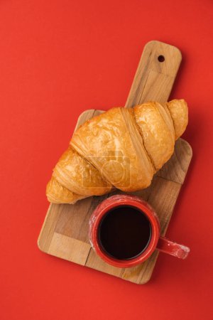 Foto de Colocación plana de croissant recién horneado sobre el fondo rojo. Pastelería tradicional francesa con una taza de café negro con un espacio de copia para un texto libre - Imagen libre de derechos