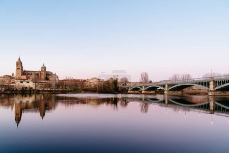 Téléchargez les photos : Scenic view of Salamanca with the Cathedral and iron bridge reflected in the Tormes River at sunset. Castilla Leon, Spain - en image libre de droit