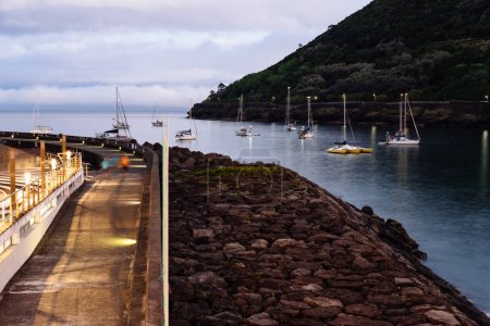 Foto de Angra Do Heroismo, Portugal - 1 de julio de 2022: Puerto de Angra do Heroismo al atardecer, Isla Terceira, Azores. Paseo marítimo por el puerto - Imagen libre de derechos