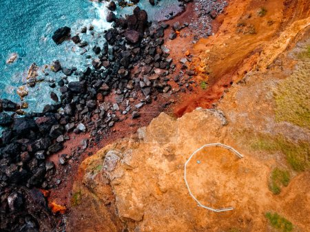 Foto de Vista aérea de un mirador en un acantilado con vistas al Océano Atlántico de roca volcánica en la costa sureste de la isla de Terceira. Imagen abstracta en colores turquesa, naranja y ocre. Azores - Imagen libre de derechos