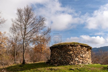 Photo for Circular shepherds hut built with slate stone in the Sierra del Rincon in Madrid during the fall. - Royalty Free Image