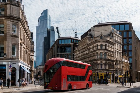 Foto de Londres, Reino Unido - 25 de agosto de 2023: Cruce en el distrito financiero de Londres con un autobús rojo de dos pisos acelerando - Imagen libre de derechos