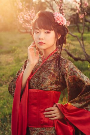 Téléchargez les photos : Asian style portrait of young woman in kimono stay in blooming garden at sunset - en image libre de droit
