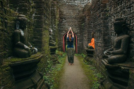 Téléchargez les photos : Spiritual travel to Myanmar. Woman in meditation pose with raised hands stay in Buddhist temple - en image libre de droit
