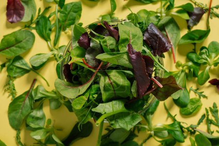 Téléchargez les photos : Pile vue de dessus de feuilles vertes vibrantes sur une surface jaune, ingrédient alimentaire végétarien pour les plats. Pose plate - en image libre de droit