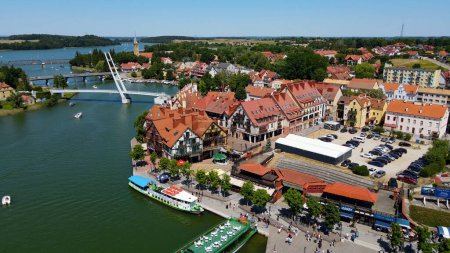 Foto de Foto aérea panorámica del dron al paisaje urbano de Mikolajki - capital de la región de Masuria en la orilla del complejo vacacional hermosa tarde de verano. Polonia, Europa. - Imagen libre de derechos