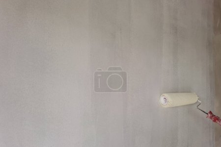 Photo for Paint roller applying white paint on wall for background - Royalty Free Image