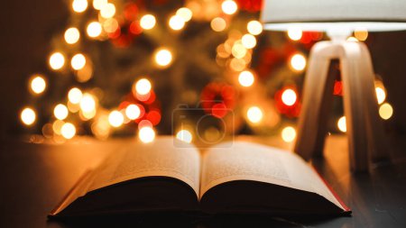 Foto de Libro que hojea en una mesa con fondo iluminado árbol de Navidad - Imagen libre de derechos