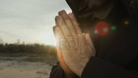 Téléchargez les photos : Les mains d'un moine priant au coucher du soleil dans la nature de campagne. - en image libre de droit