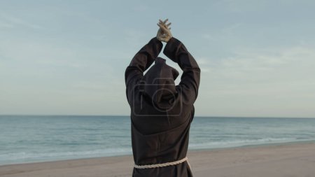 Photo for Religious Monk With Prays Towards The Sea With Open Arms.. - Royalty Free Image