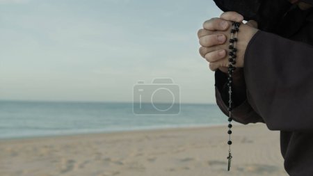 Téléchargez les photos : Mains Religieuses D'un Moine Priant Rosaire Sur La Plage. - en image libre de droit