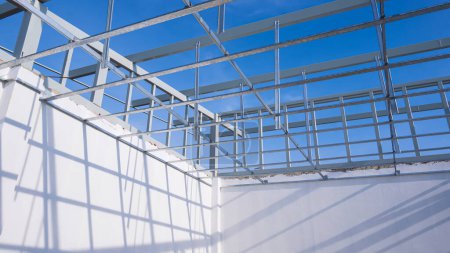 Téléchargez les photos : Structure de plafond en aluminium c-line avec mur en béton blanc dans le chantier de construction de la maison sur fond de ciel bleu, angle bas et vue en perspective - en image libre de droit