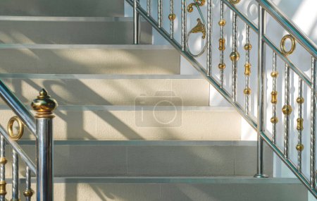 Téléchargez les photos : Lumière et ombre sur la surface des marches en tuiles beige avec rampe en acier inoxydable de l'escalier vintage - en image libre de droit
