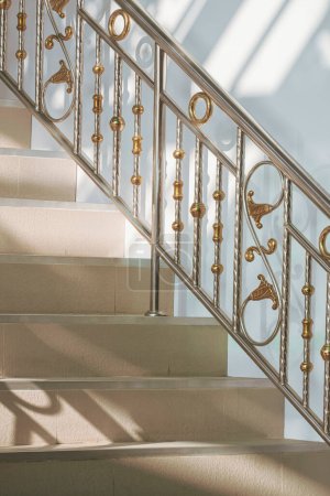 Téléchargez les photos : Lumière et ombre sur la surface de la main courante vintage en acier inoxydable avec escalier en tuile beige à l'extérieur de la maison dans un cadre vertical - en image libre de droit