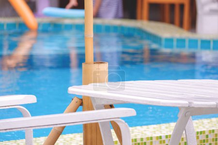 Téléchargez les photos : Table en bois blanc vide avec chaise et parasol extérieur au bord de la piscine à l'extérieur du restaurant moderne - en image libre de droit