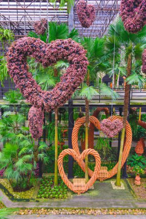 Foto de Grupo de colgante de follaje rojo en forma de corazón decorativo con plantas de palma ornamentales verdes en el hermoso jardín del cielo de Nong Nooch jardín tropical en Pattaya, Tailandia - Imagen libre de derechos