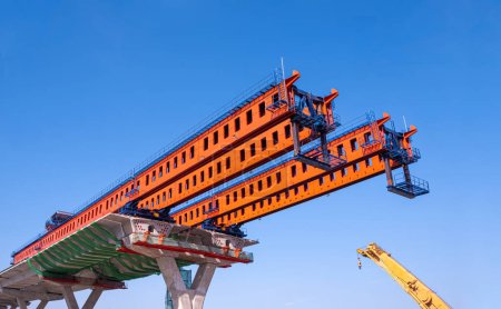 Structure de portique de lancement métallique pour l'installation d'un segment typique en béton Joint sur fondation d'une autoroute surélevée sur un chantier de construction routière sur fond bleu ciel clair