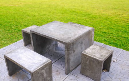 Vintage concrete loft table set with gray stone tile floor on green lawn in front yard area at home