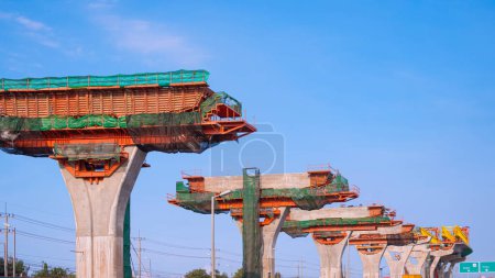 Precast segmental assembly box girder formwork on elevated expressway column structure in road construction site against blue sky background 