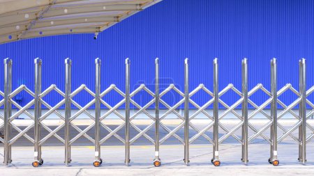 Porte-barrière automatique en acier inoxydable ou barrière pliante devant le parking et le bâtiment industriel en métal bleu