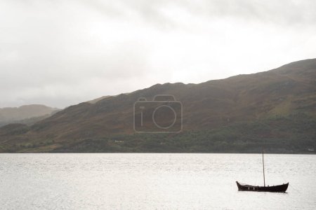 Téléchargez les photos : Bateau naviguant seul dans un lac des Highlands, Écosse - en image libre de droit