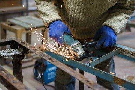 Téléchargez les photos : Travailleur utilisant meuleuse d'angle dans l'usine et de lancer des étincelles - en image libre de droit