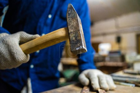 Téléchargez les photos : Un homme travaille avec un marteau dans un atelier. - en image libre de droit