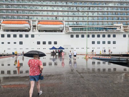 Téléchargez les photos : Les gens marchent sur le quai vers un grand paquebot de croisière britannique à Kralendijk, un jour de pluie, Janvier 2023 - en image libre de droit
