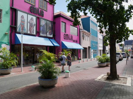 Téléchargez les photos : Des gens passent devant des boutiques dans une rue colorée de Willemstad, la capitale de Curaçao, aux Antilles néerlandaises - en image libre de droit