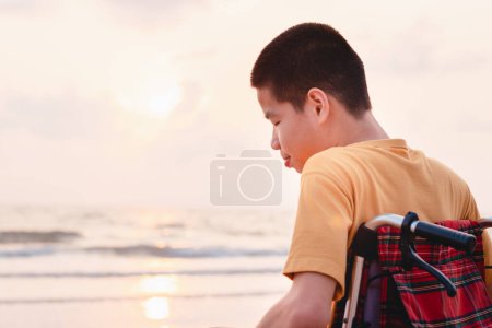 Foto de Niño asiático con cara feliz en la playa del mar puesta del sol, Hermoso momento de la naturaleza, Viajar con una silla de ruedas para aprender sobre el mundo sin límites con el apoyo de la familia, Buena salud mental, foto positiva - Imagen libre de derechos
