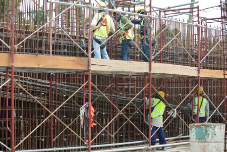 Foto de SELANGOR, MALASIA - 23 DE OCTUBRE DE 2015: Trabajadores de la construcción que fabrican barras de refuerzo de acero para muros de hormigón en la obra de Selangor, Malasia. La barra de refuerzo diseñada por el ingeniero
. - Imagen libre de derechos