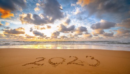Number 2023 written on seashore sand at sunrise. Concept of upcoming new year and passing of time.