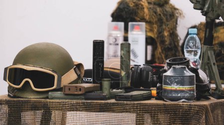 Foto de Helmet, ammunition, gas mask, military equipment on a camouflage net on the table. High quality photo - Imagen libre de derechos