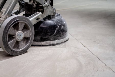 Photo for Concrete floor grinding machine is an essential tool used to prepare the surface of a concrete floor before the installation of a new layer. Its powerful motor and diamond-tipped grinding discs are effective in removing unevenness and smoothing out i - Royalty Free Image