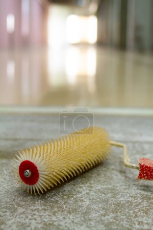 Photo for A spiked roller is a tool commonly used to remove air bubbles from freshly poured epoxy flooring. - Royalty Free Image