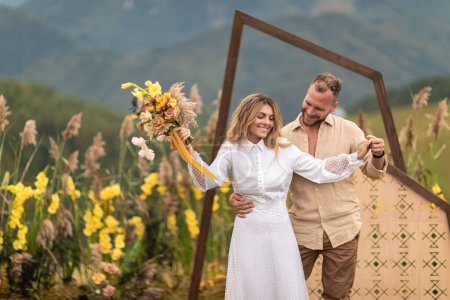 Photo for Natural beauty and simplicity of a couple who eloped in the mountains surrounded by natural decor and flowers. The bride is wearing a beautiful white dress and both are beaming with joy and love. - Royalty Free Image