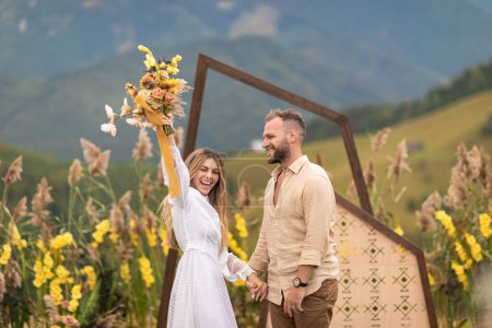 Photo for Natural beauty and simplicity of a couple who eloped in the mountains surrounded by natural decor and flowers. The bride is wearing a beautiful white dress and both are beaming with joy and love. - Royalty Free Image